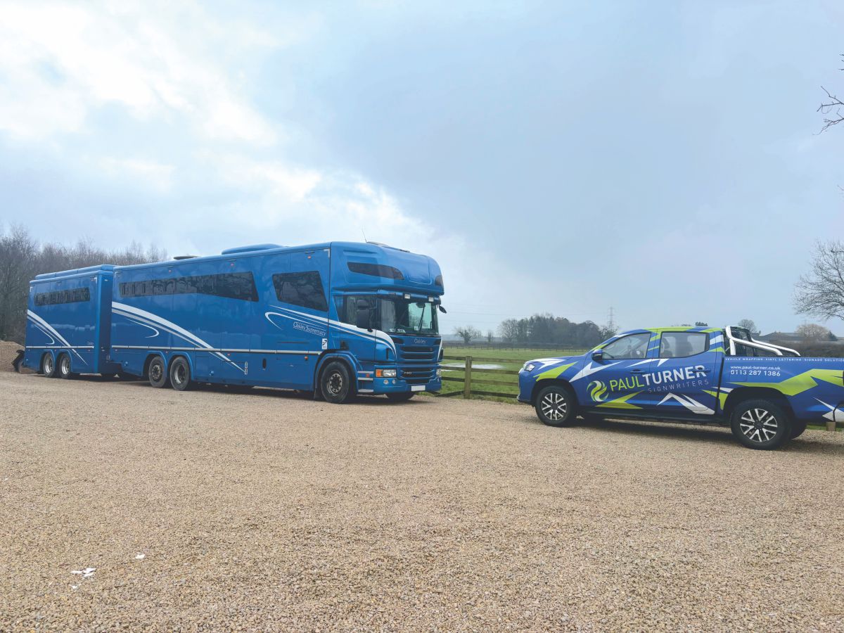 Paul Turner Signwriters team measuring a large blue horsebox and trailer on site for a custom vinyl wrap installation.